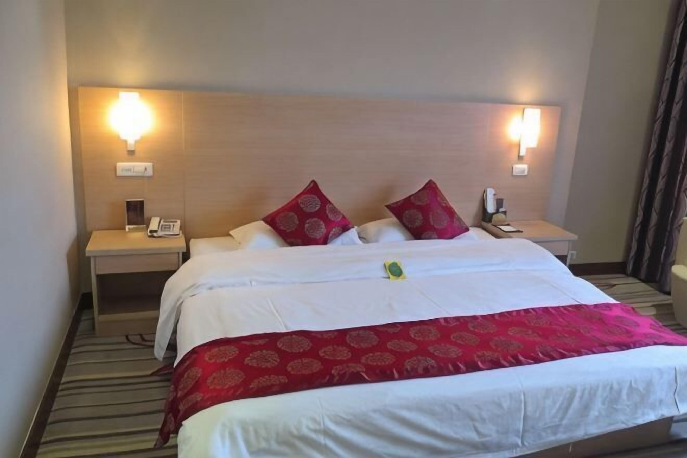 Una habitación de hotel con una cama grande, dos mesitas de noche y una lámpara.