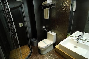 A bathroom with a shower, toilet, sink, and a tiled wall.