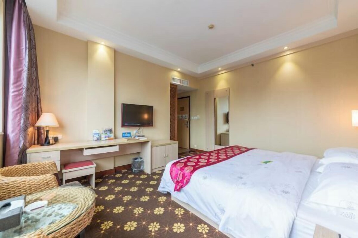 Una habitación de hotel con una cama, un escritorio, una silla, un televisor y un espejo.