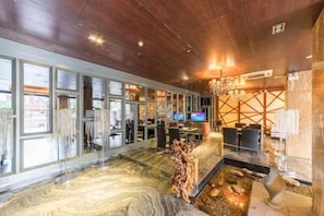 A modern hotel lobby with a marble floor, a central water feature, and a television screen. - Jinhai'an Sunshine Holiday Hotel (Yongfu)