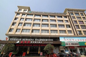 A multi-story hotel building with a sign for 'JINHAIEN SENSHINE HOLIDAY HOTEL' and a smaller sign for 'SHANGHAI HOTEL'. - Jinhai'an Sunshine Holiday Hotel (Yongfu)