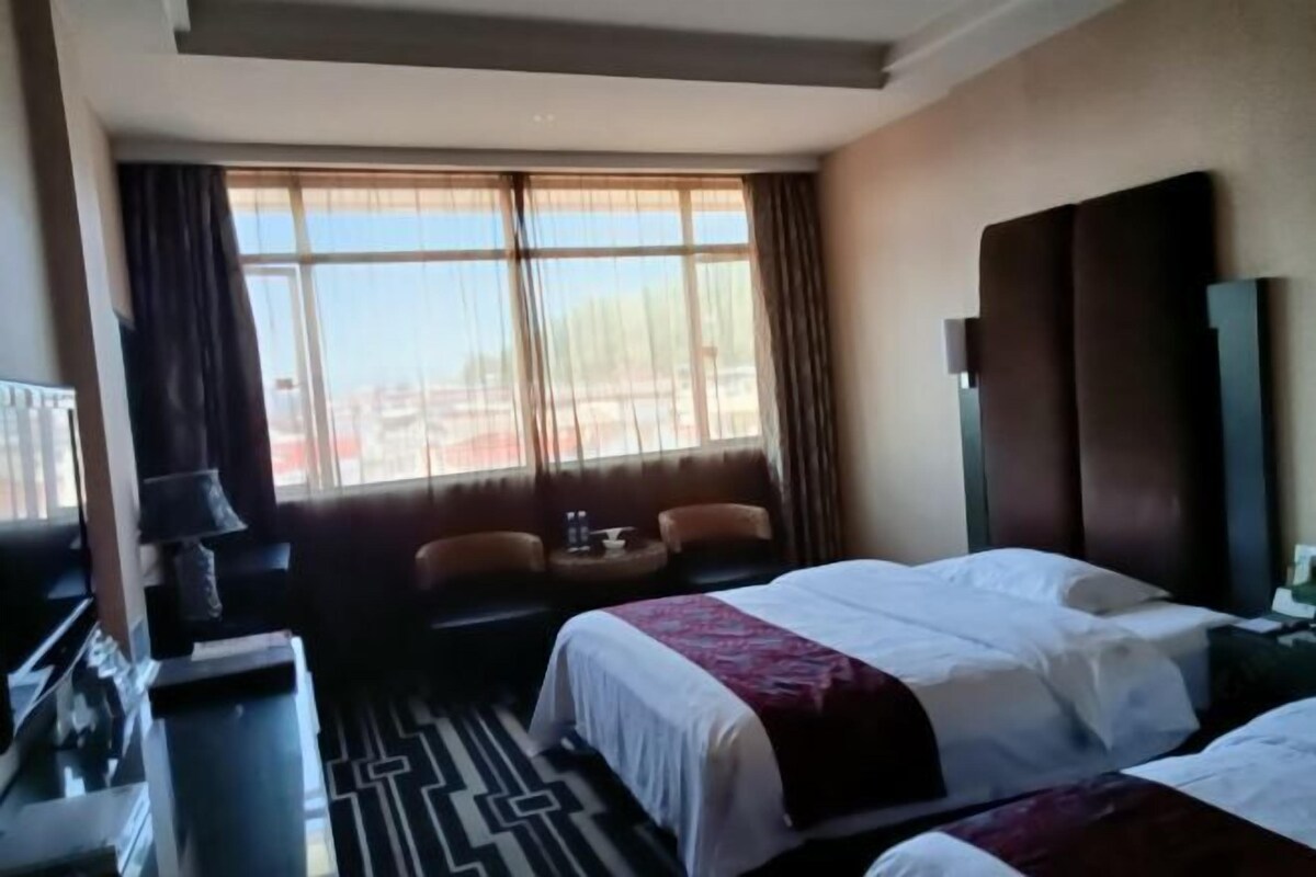 Una habitación de hotel con una cama grande, un sofá, una mesita y un televisor.