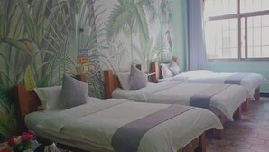 A room with three beds, a large window, and a wall with a tropical plant mural. - Nianlun Theme Hotel (Ninglang)