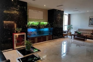 A lobby with a reception desk, a fish tank, a sofa, and a coffee table.