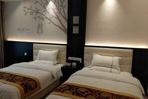 A hotel room with two beds, a wall mural, and a nightstand with a phone.