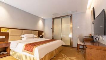 A hotel room with a large bed, a desk, a chair, a television, and a sliding door.