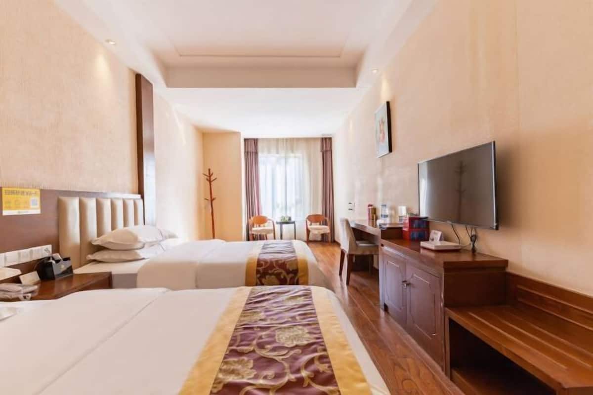 Une chambre d’hôtel avec deux lits, un bureau, une télévision et une chaise.