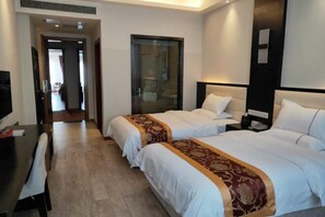 A hotel room with two beds, a desk, a chair, and a television.