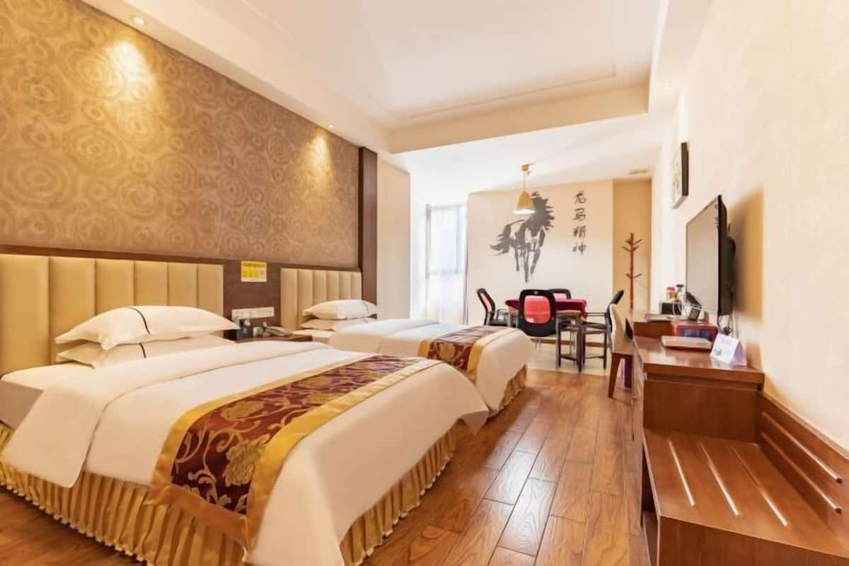 Une chambre d’hôtel avec deux lits, un bureau et une chaise.