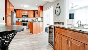 A modern kitchen with wooden cabinets, stainless steel appliances, and a large island. - 19th - Aunies Place · Totally Updated Pool/FUN/Beaches (Bradenton)