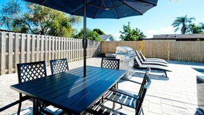 An outdoor patio with a table and chairs, a grill, and a covered seating area. - 19th - Aunies Place · Totally Updated Pool/FUN/Beaches (Bradenton)