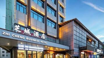 A modern hotel building with a sign reading 'ZHENG BUSINESS HOTEL.'