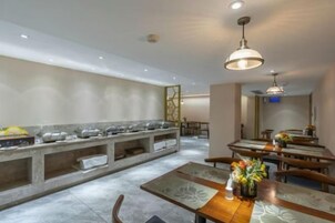 Comedor de hotel con barra libre, varias mesas y una estación central de servicio.