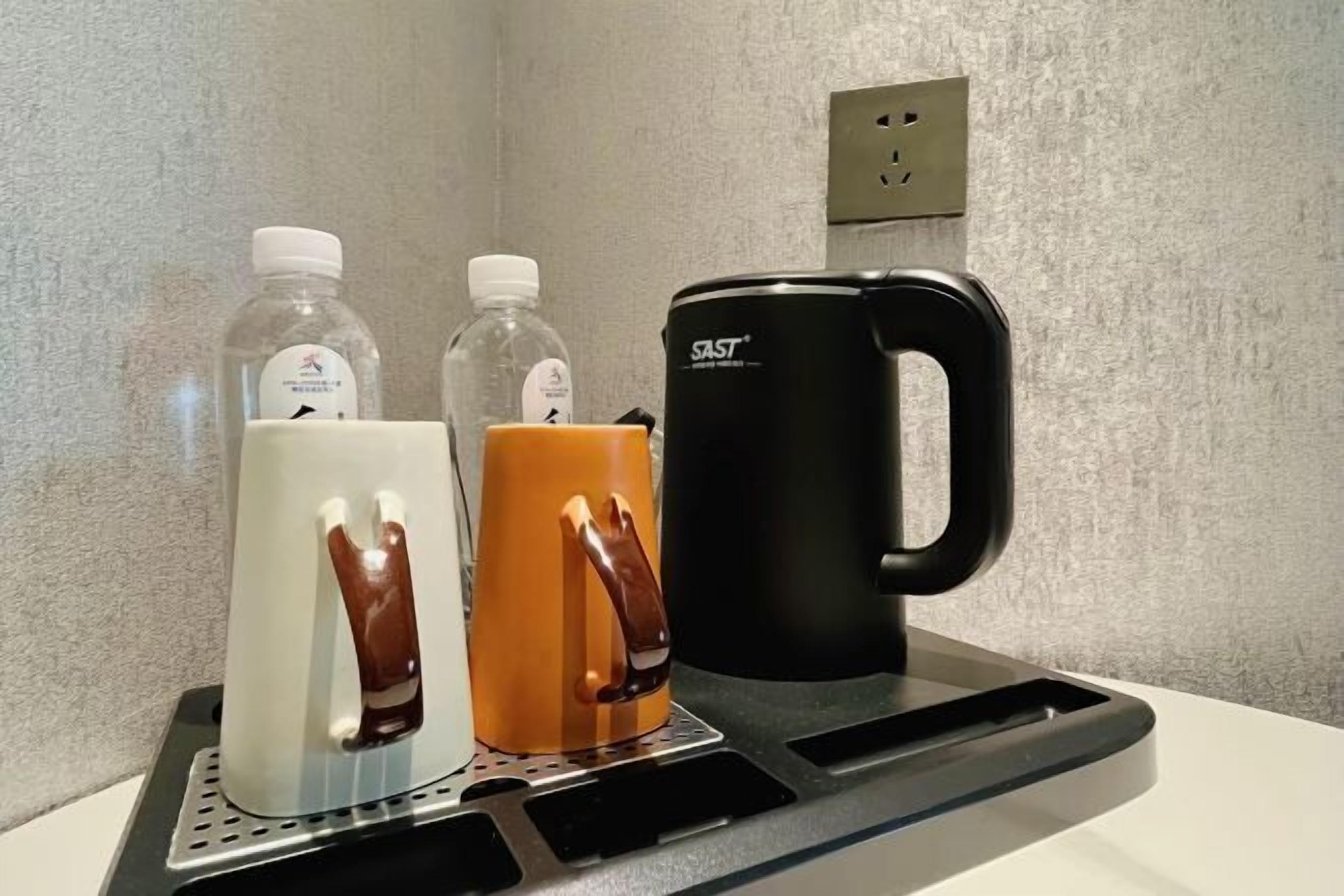 Eine Arbeitsplatte mit einer Kaffeemaschine, zwei Flaschen und einer Tasse.