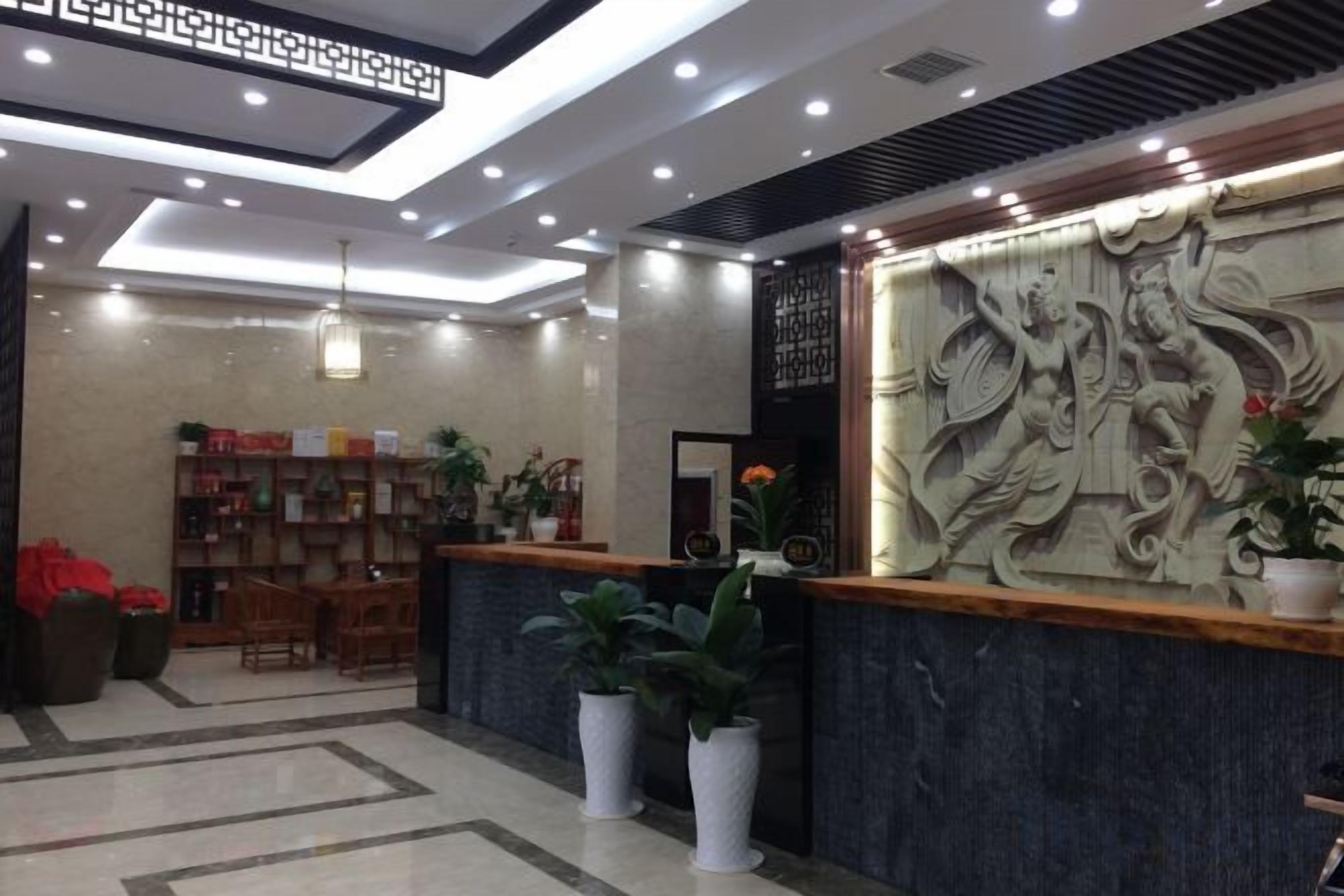 A reception area with a reception desk, potted plants, and a decorative wall.