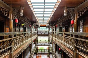 Un corridoio in legno tradizionale con una passerella centrale, ringhiere elaborate e lanterne sospese.