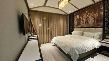 Una habitación de hotel moderna con una cama grande, un televisor de pantalla plana montado en la pared, una mesita de noche y un cuadro decorativo.