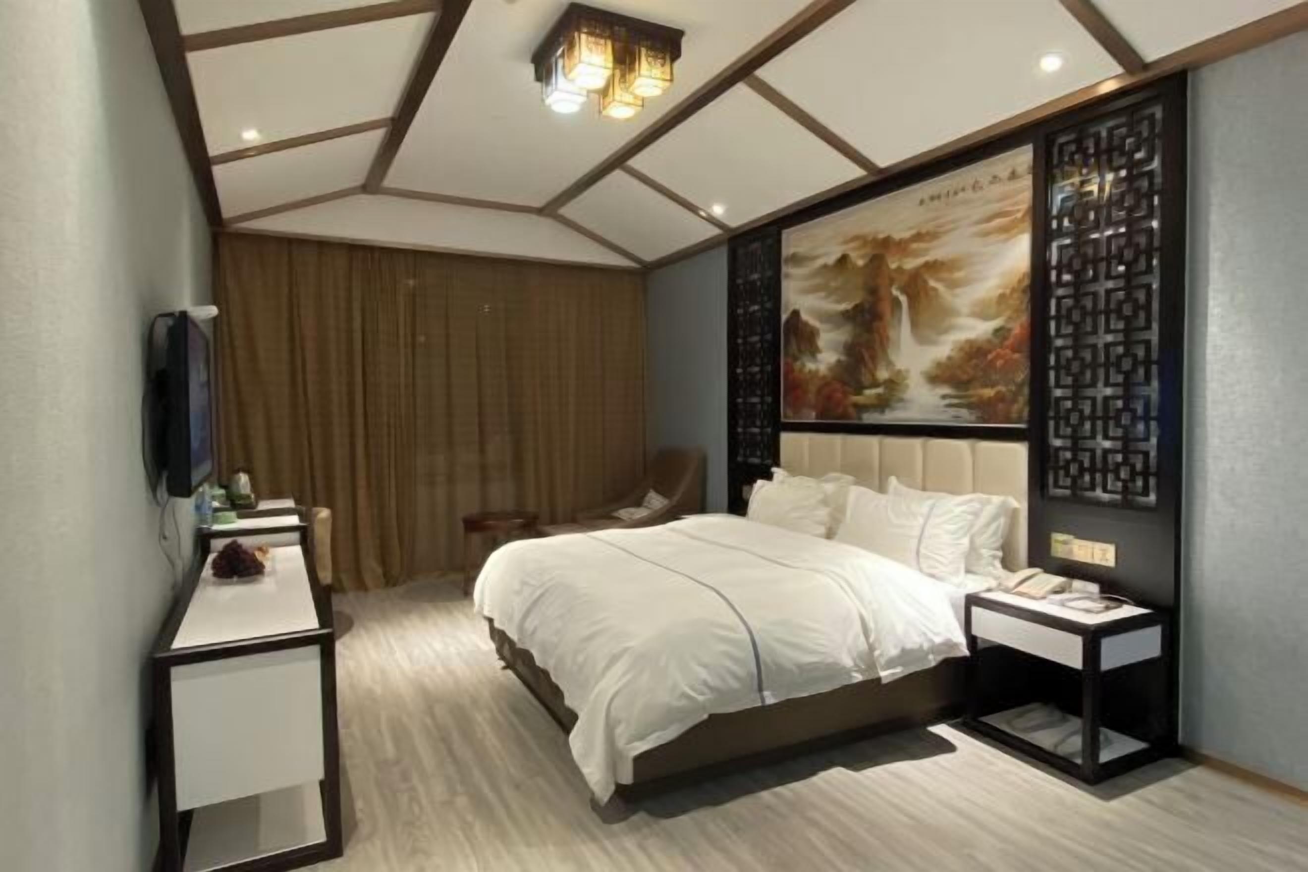 A modern bedroom with a bed, bedside tables, a chair, a TV, and a decorative wall panel.