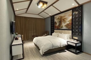 A modern bedroom with a bed, bedside tables, a chair, a TV, and a decorative wall panel. - Zijin Haoting Hotel (Renhuai)