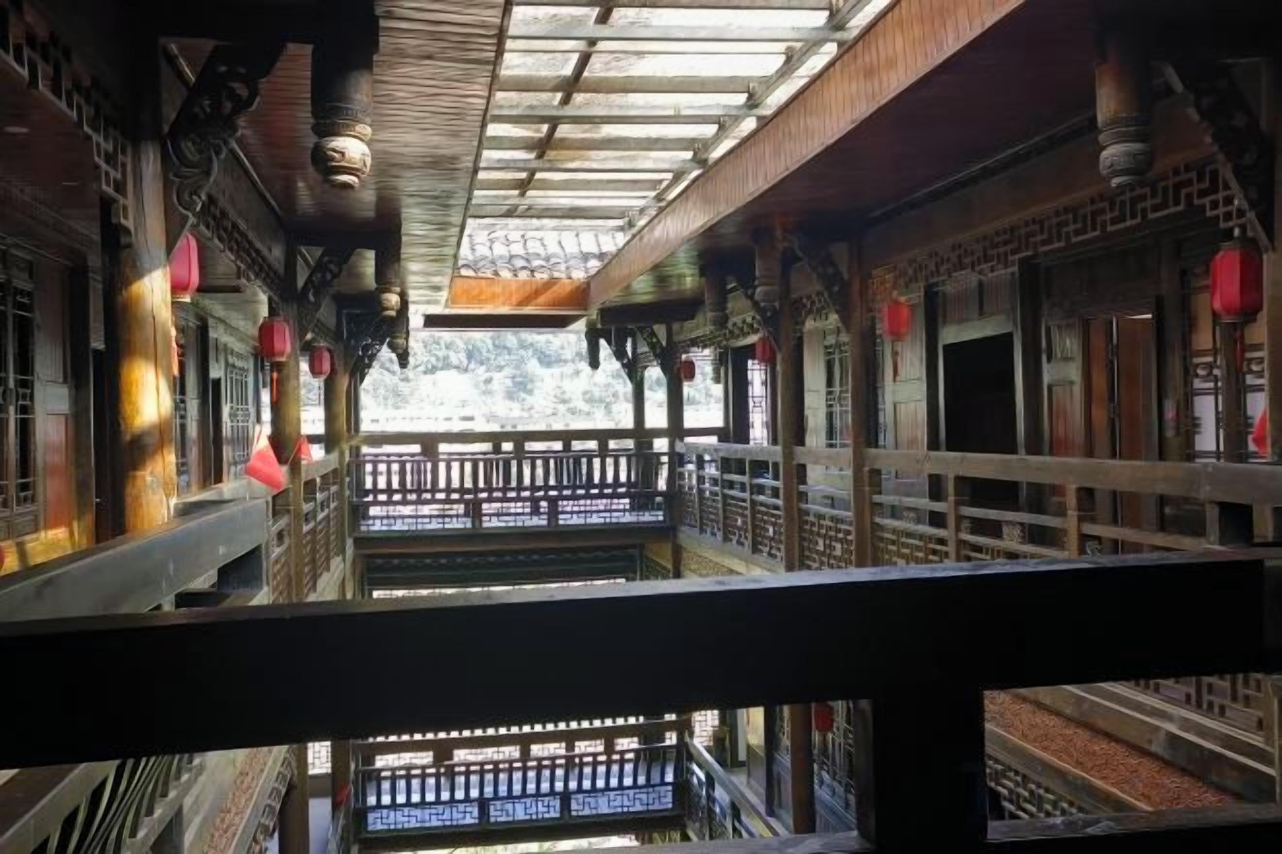 A traditional architectural corridor with wooden railings and a view of a mountainous landscape.