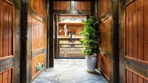 A wooden corridor with a tiled floor leading to a reception area with a patterned screen. - Zijin Haoting Hotel (Renhuai)