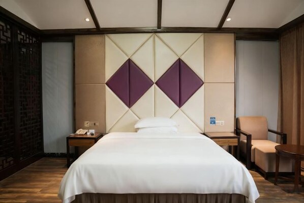 A hotel room with a large bed, a desk with a phone, a chair, and a small table. - Zijin Haoting Hotel (Renhuai)