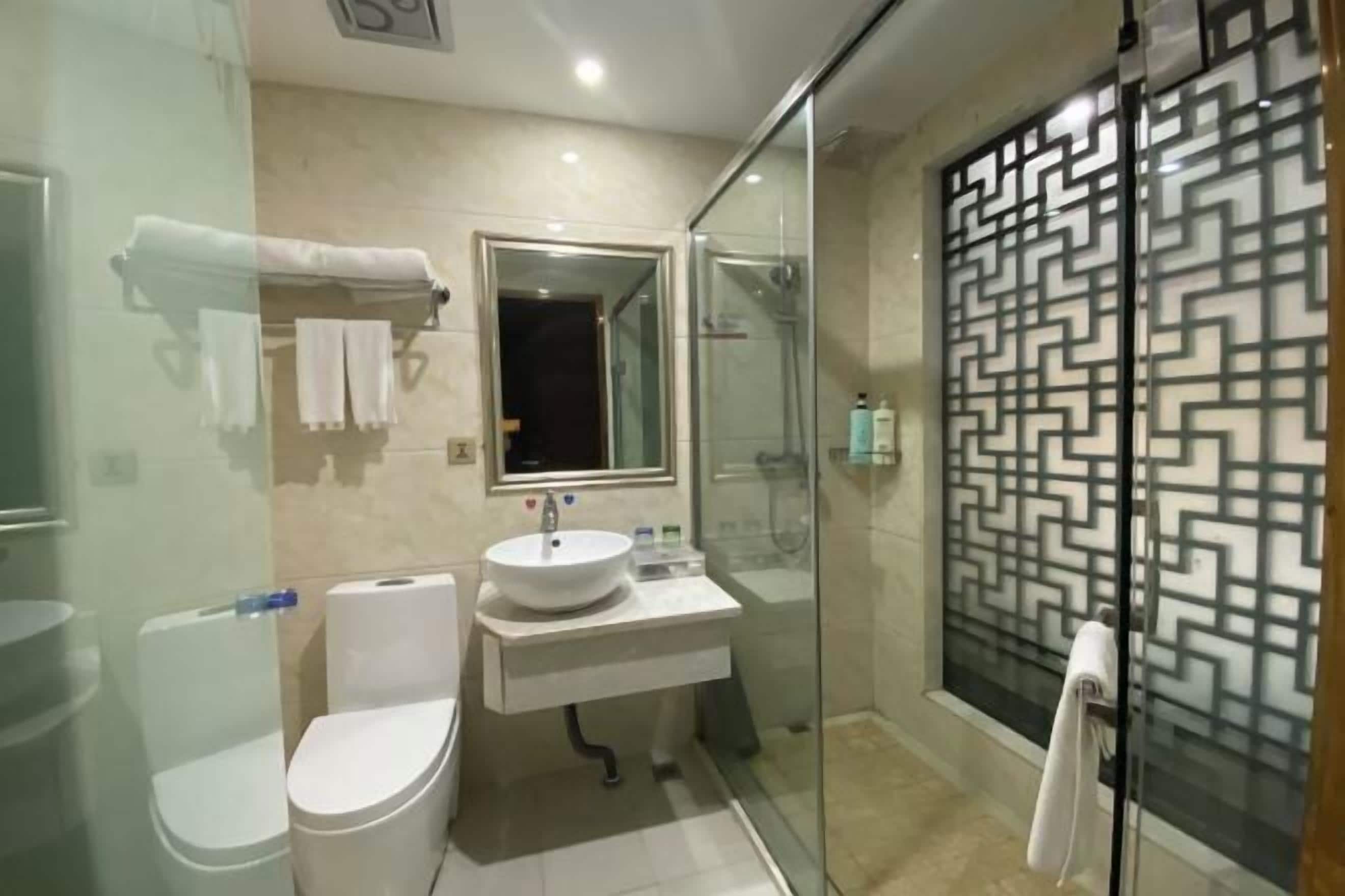 A modern bathroom with a glass-enclosed shower, a white sink, and a toilet.