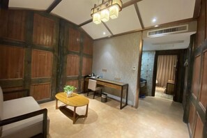 A room with a wooden desk, a chair, a small table with a plant, and a hanging light fixture. - Zijin Haoting Hotel (Renhuai)