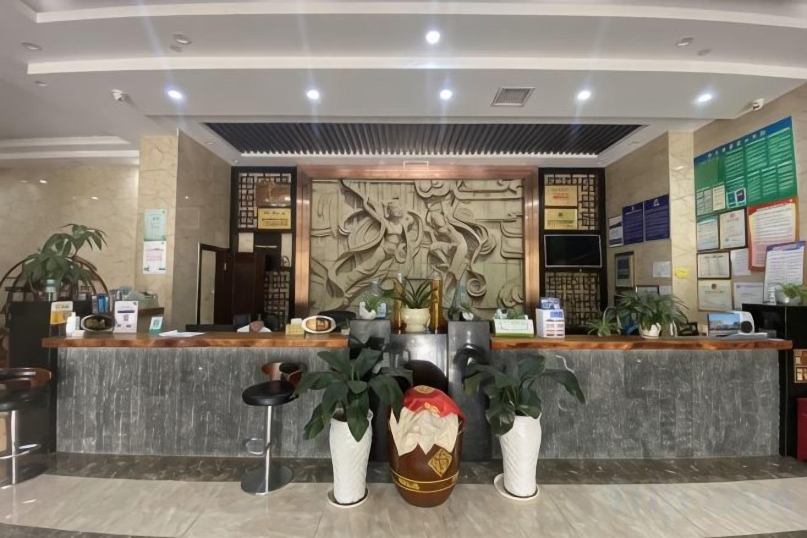 A reception area with a marble counter, potted plants, and a decorative wall.