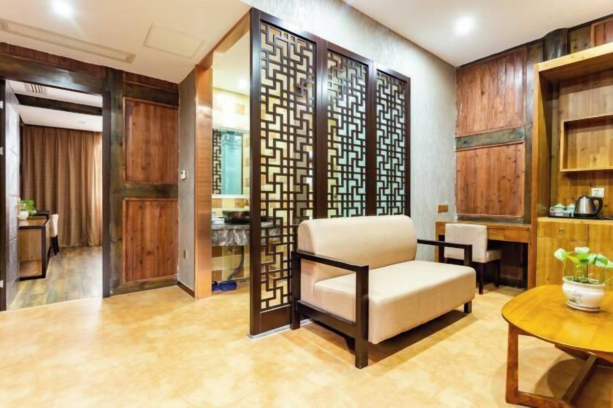 A modern living room with a beige sofa, a wooden coffee table, and a decorative partition with geometric patterns.