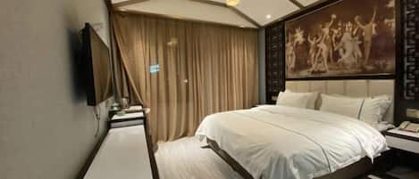 A modern hotel room with a large bed, a flat-screen TV, a bedside table, and a decorative wall piece.