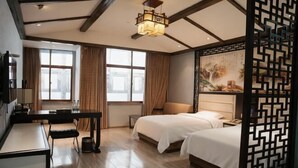 A hotel room with two beds, a desk, a chair, a TV, and a decorative screen. - Zijin Haoting Hotel (Renhuai)