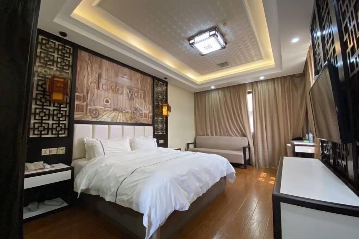 A hotel room with a large bed, a desk, and a wall with a decorative panel.
