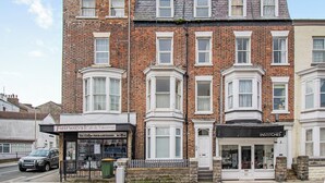 A two-story brick building with a cafe and a shop on the ground floor. - This ground floor apartment is less than a 10-minute walk away from the beach. (Scarborough)