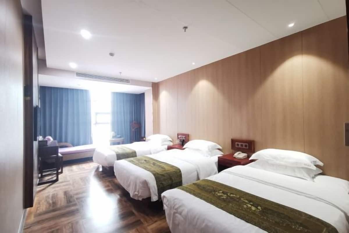 Ein Hotelzimmer mit zwei Betten, Holzwandverkleidung, einem Schreibtisch und einem Stuhl.