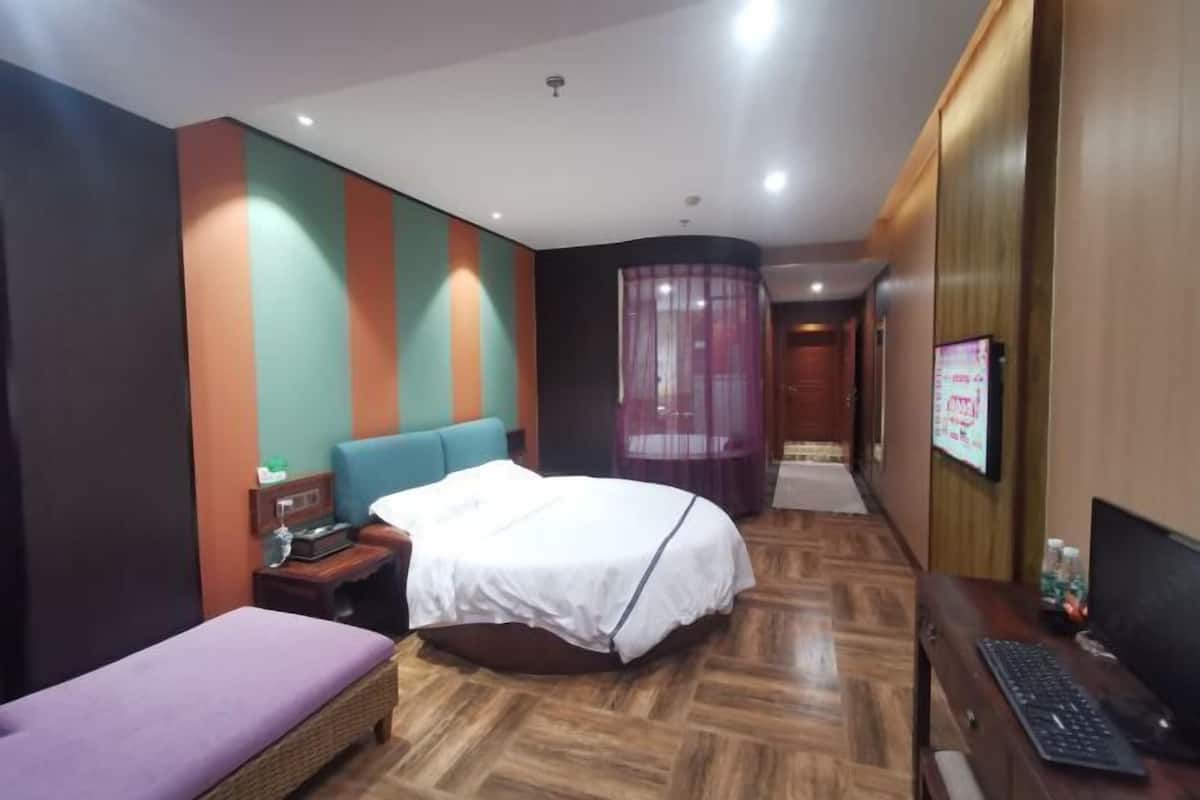 Ein Hotelzimmer mit Bett, einer kleinen Couch, einem Schreibtisch mit Computer und einem Fernseher.