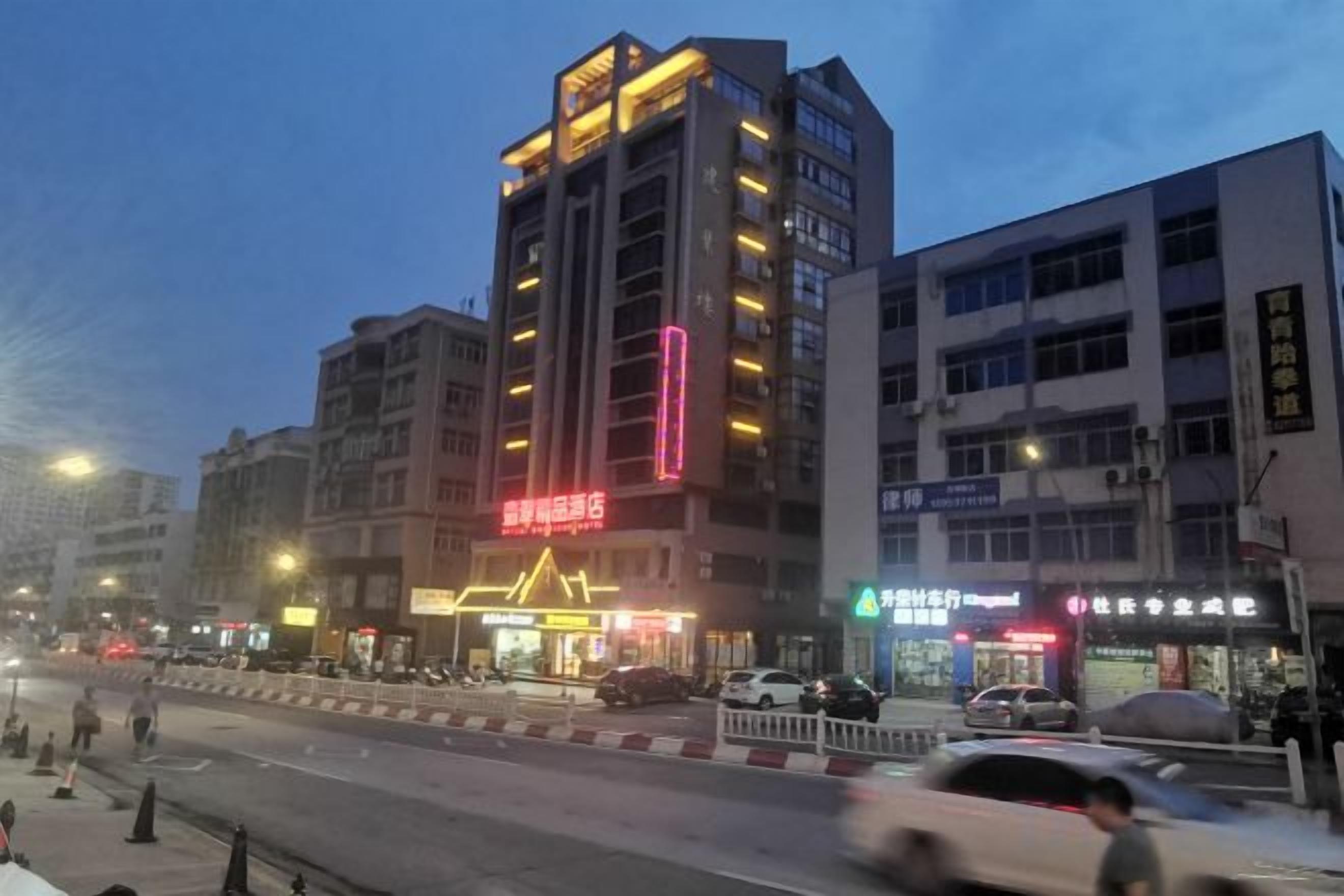 A multi-story building with illuminated signage, a street in front, and vehicles in motion.