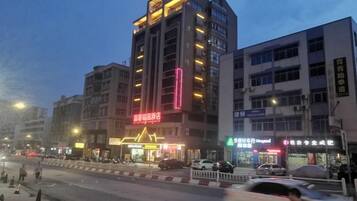 A multi-story building with illuminated signage, a street in front, and vehicles in motion.