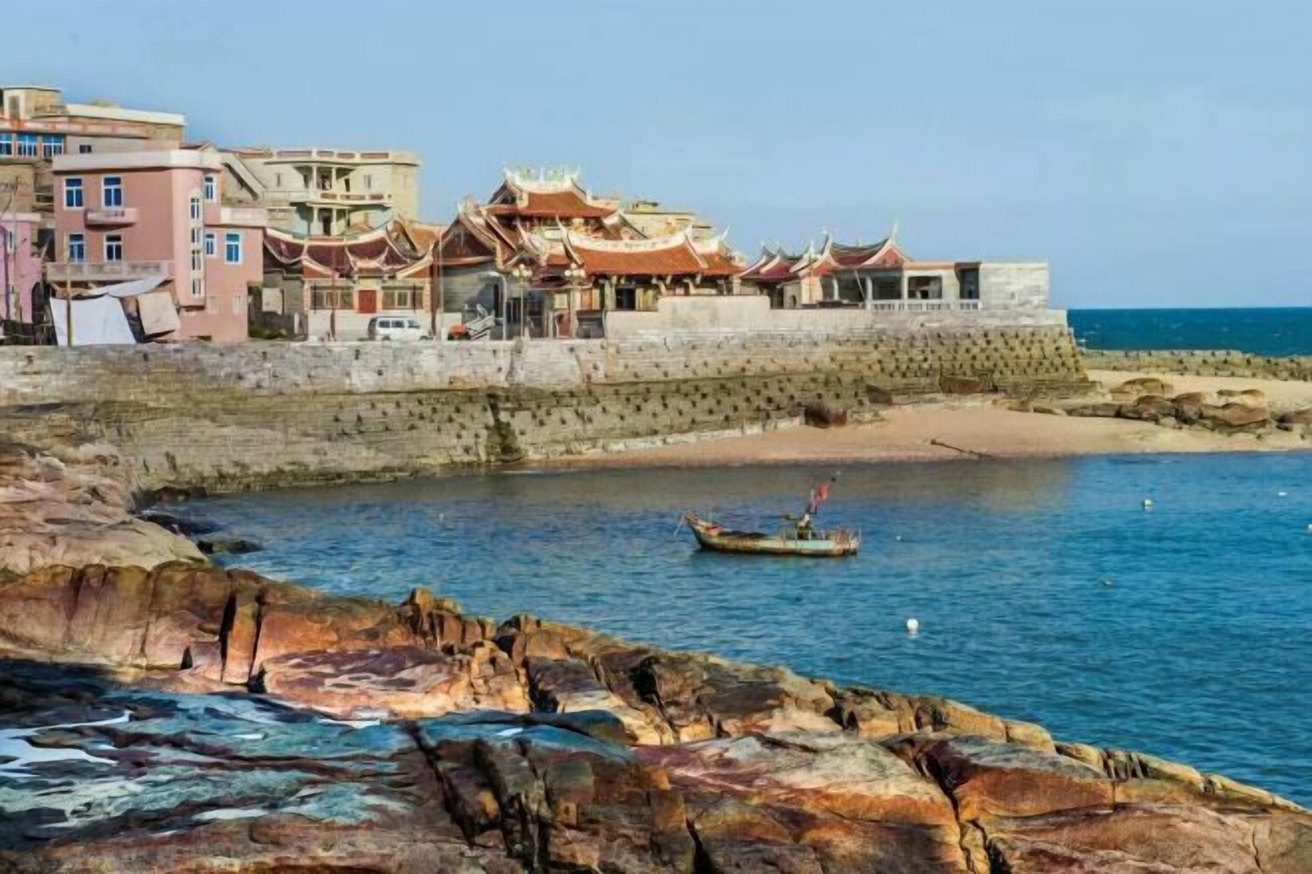 A coastal town with traditional architecture, a rocky shoreline, and a small boat in the water.