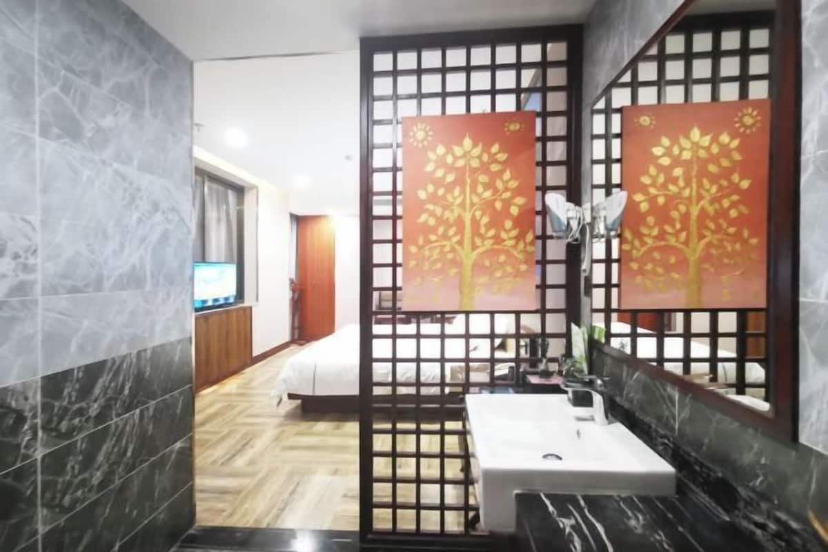 Ein modernes Badezimmer mit Marmorwaschbecken, einem großen Spiegel und dekorativen Wandfeldern mit Baummotiven.