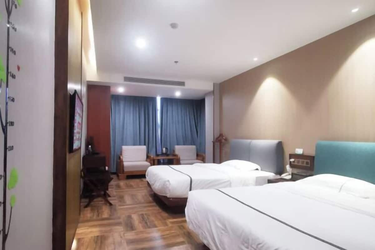 Ein Hotelzimmer mit zwei Betten, einem Schreibtisch, einem Stuhl und einem fenster mit Vorhängen.