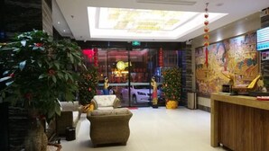 A lobby with a reception desk, a large potted plant, wicker furniture, and a mural on the wall. - Feicui Boutique Hotel (Jinjiang)