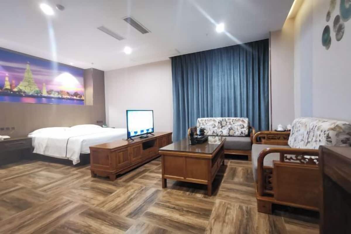 Ein Hotelzimmer mit Bett, Schreibtisch, Stuhl, einer Couch und einem großen Fenster mit Vorhängen.