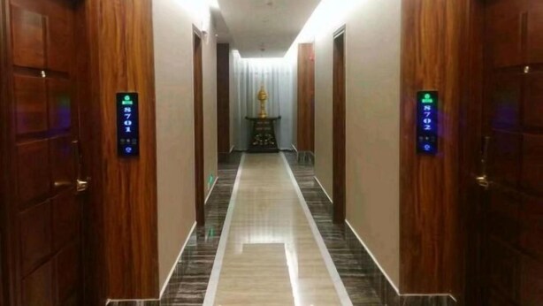 A hotel corridor with wooden doors, a marble floor, and a central light fixture. - Feicui Boutique Hotel (Jinjiang)