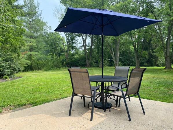 Une table ronde avec quatre chaises et un parasol bleu.