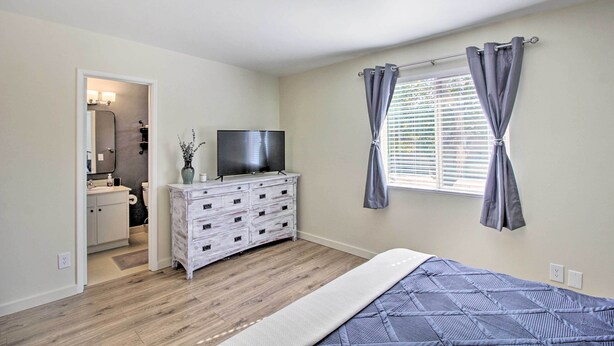 A bedroom with a bed, a dresser, a television, and a window with curtains. - Fire Pit & Grill! Tucson Family Home, Walk to Park (Tucson)