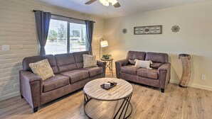A living room with two brown leather sofas, a round coffee table, a ceiling fan, and a tall woven floor lamp. - Fire Pit & Grill! Tucson Family Home, Walk to Park (Tucson)