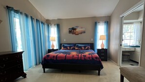 Una camera da letto con un letto, una cassettiera, una scrivania e una ventola a soffitto.