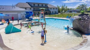 A water play area with slides and water jets, surrounded by a pool and a large rock feature.