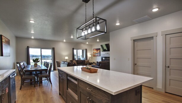 A modern kitchen with a large island, wooden cabinets, and a dining area with a table and chairs.